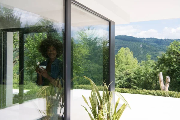 Afroamerikanerin trinkt Kaffee und schaut aus dem Fenster — Stockfoto