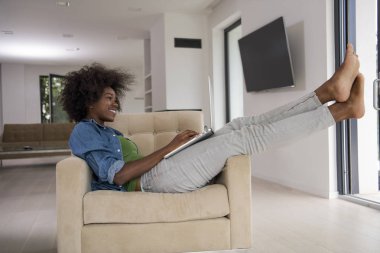 Bir dizüstü bilgisayar kullanarak sandalyede Afrikalı-Amerikalı kadınlar evde