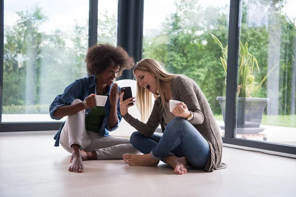 Multietniskt kvinnor sitta på golvet och dricka kaffe — Stockfoto