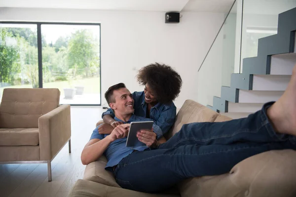 Pareja multiétnica que se relaja en casa con tabletas — Foto de Stock