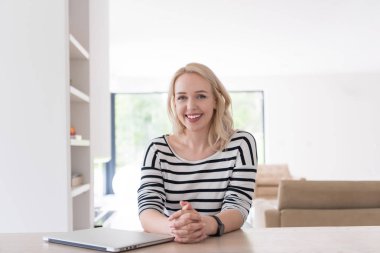 Evde dizüstü bilgisayarı olan genç bir kadın.