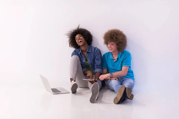 Πολυεθνική ζευγάρι κάθεται στο πάτωμα με ένα φορητό υπολογιστή και tablet — Φωτογραφία Αρχείου
