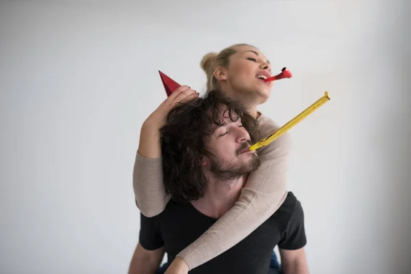 Couple in party hats blowing in whistle — Stock Photo, Image