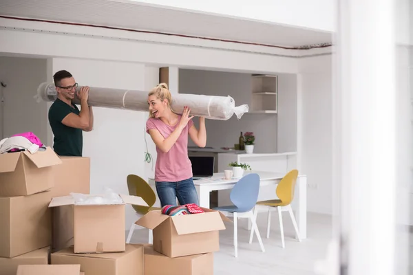 Casal carregando um tapete se mudando para casa nova — Fotografia de Stock