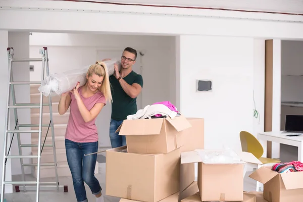 Casal carregando um tapete se mudando para casa nova — Fotografia de Stock