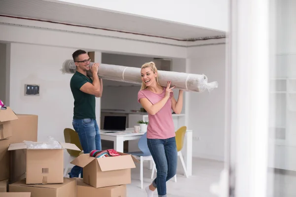Casal carregando um tapete se mudando para casa nova — Fotografia de Stock