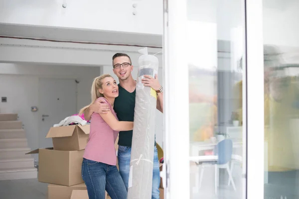 Casal carregando um tapete se mudando para casa nova — Fotografia de Stock