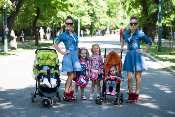 Gemelas madre con niños en el parque de la ciudad — Foto de Stock