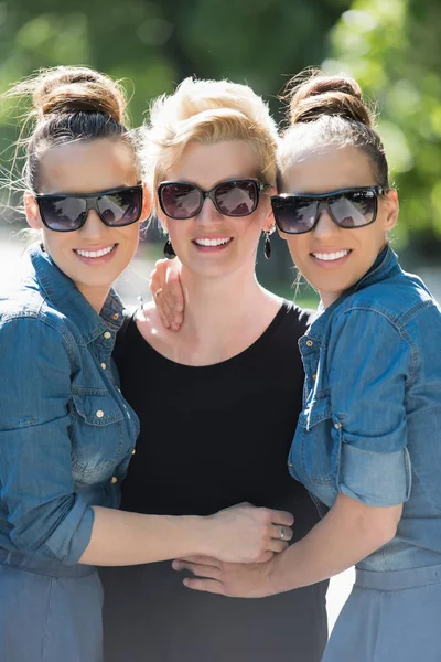Retrato de tres mujeres jóvenes y hermosas con gafas de sol — Foto de Stock