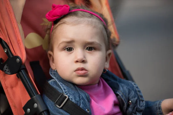 Meisje van de baby in de kinderwagen zitten — Stockfoto