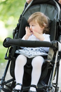 Anne bebek kızı bir bebek arabası itti.