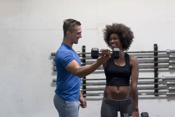 Černá žena dělá bicep kroutí s fitness trenérem — Stock fotografie