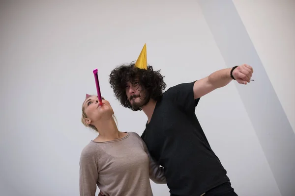 Casal em chapéus de festa soprando no apito — Fotografia de Stock