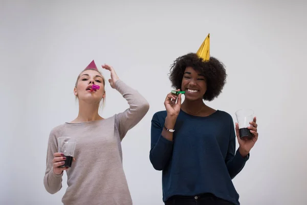 Mulheres sorridentes em bonés de festa soprando para assobios — Fotografia de Stock