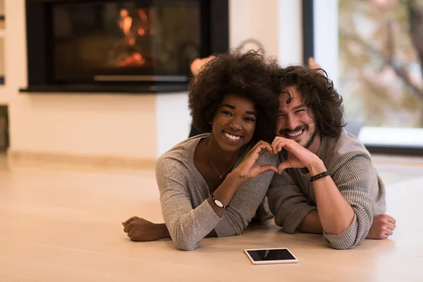 Couple multiethnique montrant un cœur avec les mains sur le sol — Photo