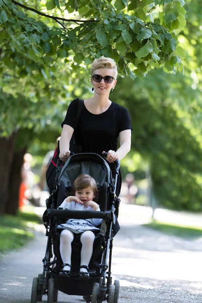 Mamma sköt dottern baby i en barnvagn — Stockfoto