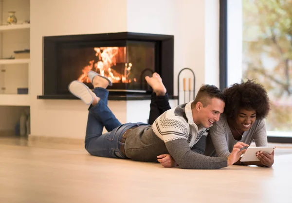 Multiethnisches Paar nutzt Tablet-Computer auf dem Fußboden — Stockfoto