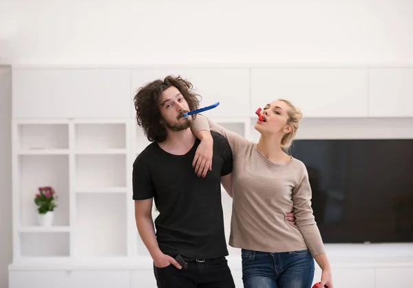 Casal em chapéus de festa soprando no apito — Fotografia de Stock