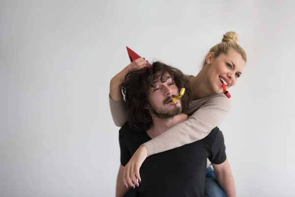 Couple in party hats blowing in whistle — Stock Photo, Image