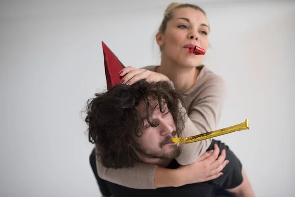 Couple in party hats blowing in whistle — Stock Photo, Image