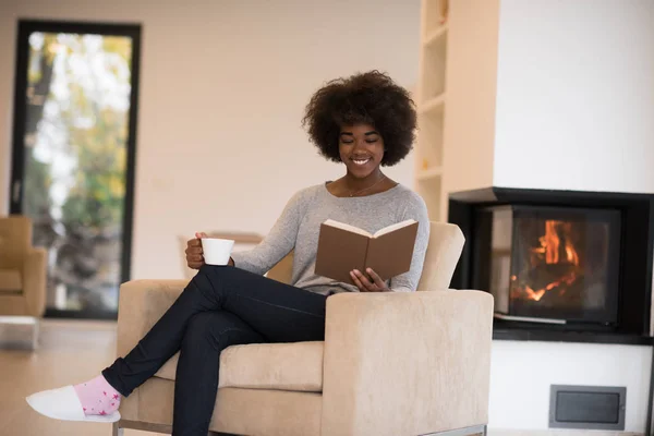 Чорна жінка читає книгу перед каміном — стокове фото