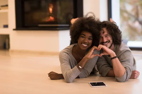 Couple multiethnique montrant un cœur avec les mains sur le sol — Photo