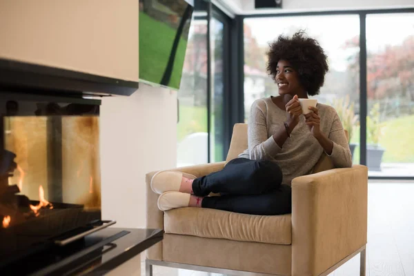 Mujer negra bebiendo café frente a la chimenea —  Fotos de Stock