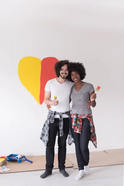 Couple with painted heart on wall — Stock Photo, Image