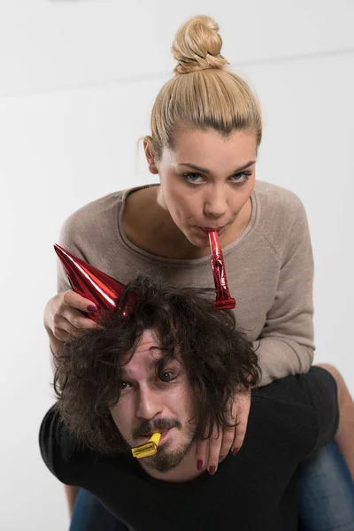 Couple in party hats blowing in whistle — Stock Photo, Image