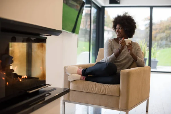 Mujer negra bebiendo café frente a la chimenea — Foto de Stock