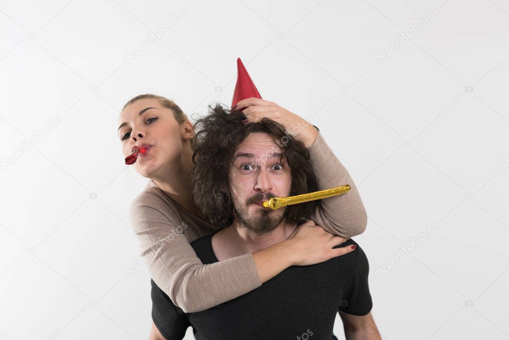 couple in party hats blowing in whistle