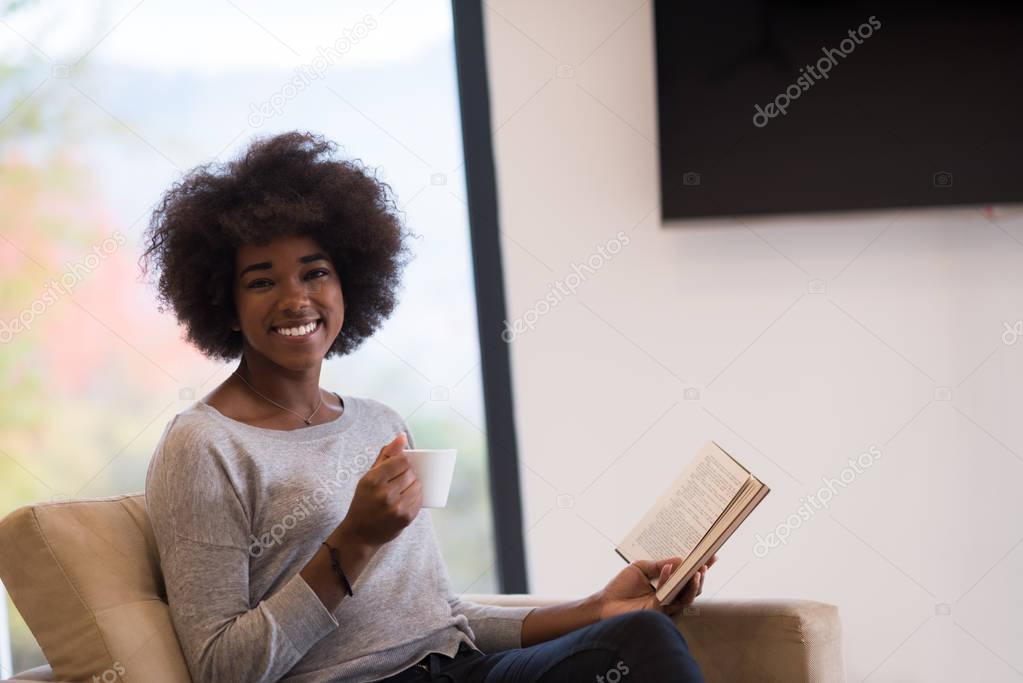black woman reading book  in front of fireplace