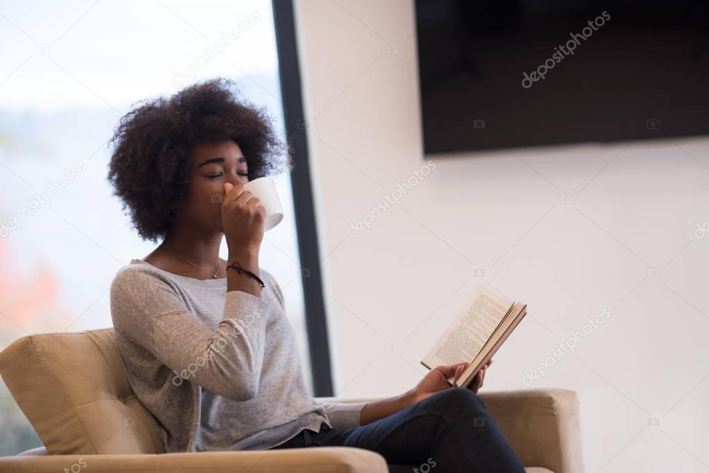 black woman reading book  in front of fireplace