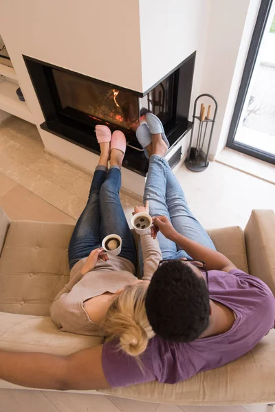 Pareja joven multiétnica frente a la chimenea — Foto de Stock