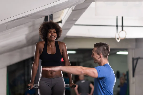 Black woman doing parallel bars Exercise with trainer — Stock Photo, Image