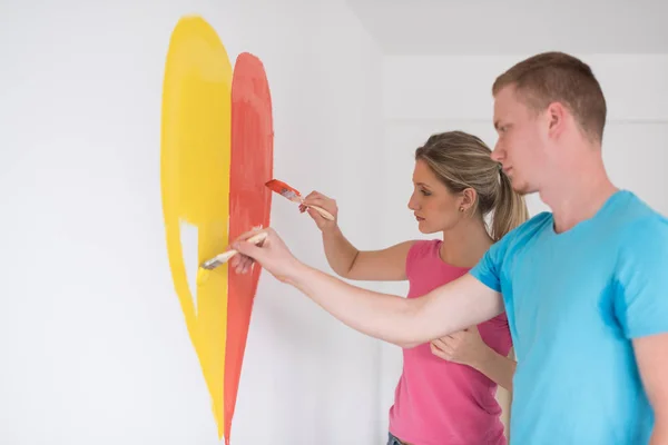 Couple painting heart on wall — Stock Photo, Image