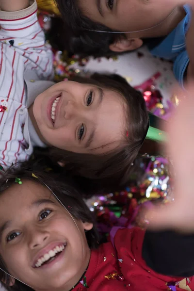 Yerde yatarken konfeti üfleme çocuklar — Stok fotoğraf