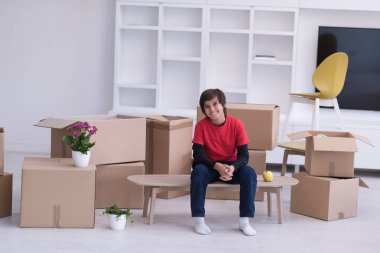 onun etrafında karton kutular ile masaya oturan çocuk