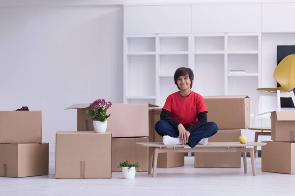 boy sitting on the table with cardboard boxes around him