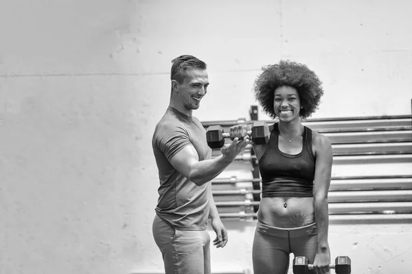 Черная женщина делает бицепсы с тренером по фитнесу — стоковое фото