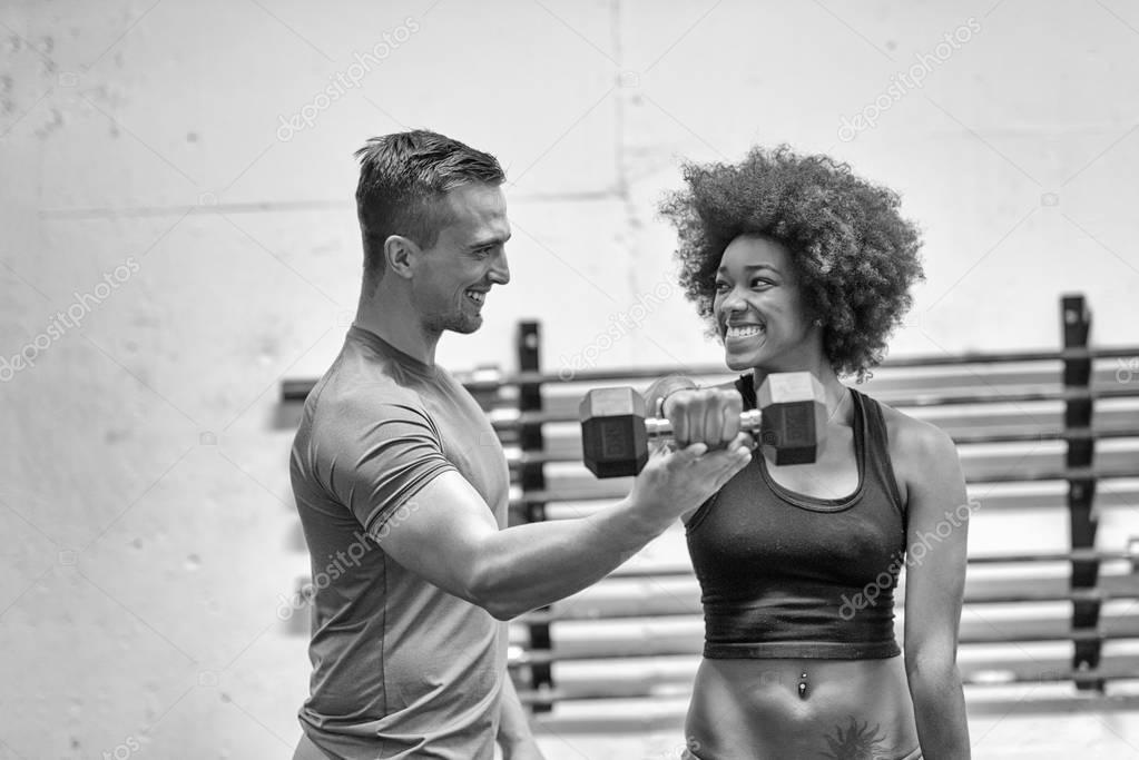 black woman doing bicep curls with fitness trainer