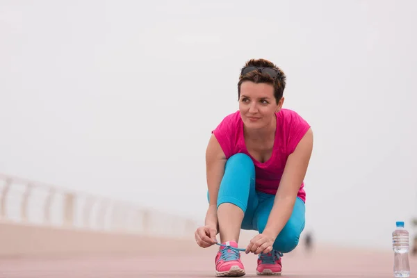 Giovane donna allacciatura lacci delle scarpe da ginnastica — Foto Stock