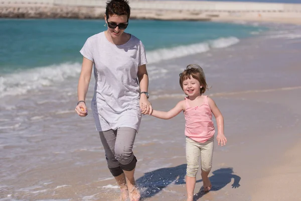 Mutter und Tochter rennen am Strand — Stockfoto