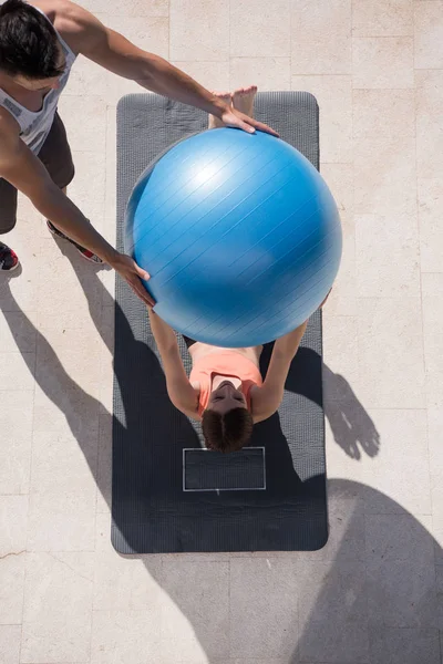 Vrouw en persoonlijke trainer doen oefening met pilates bal — Stockfoto
