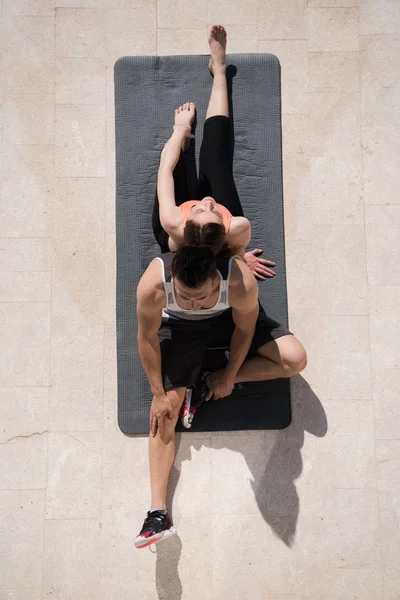 Mujer con entrenador personal haciendo ejercicios de yoga por la mañana top vie — Foto de Stock