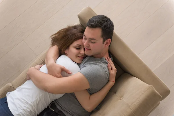 Jovem casal bonito abraçando no sofá — Fotografia de Stock