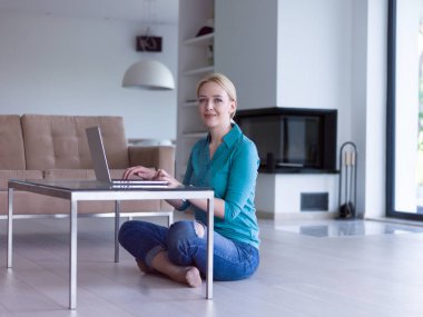 genç kadın yerde dizüstü bilgisayar kullanan