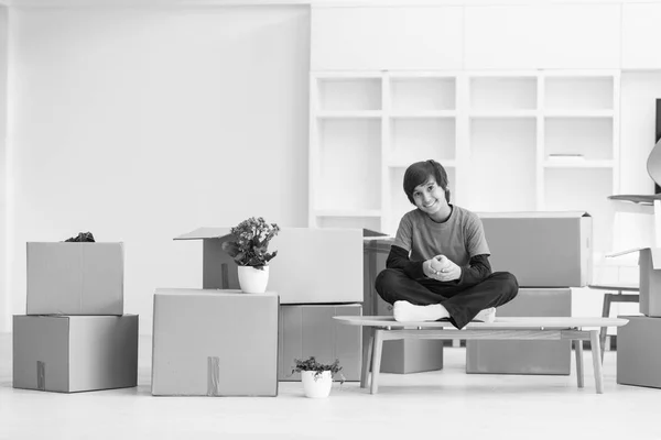 Ragazzo seduto sul tavolo con scatole di cartone intorno a lui — Foto Stock