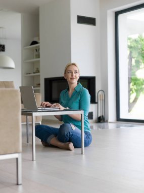 genç kadın yerde dizüstü bilgisayar kullanan