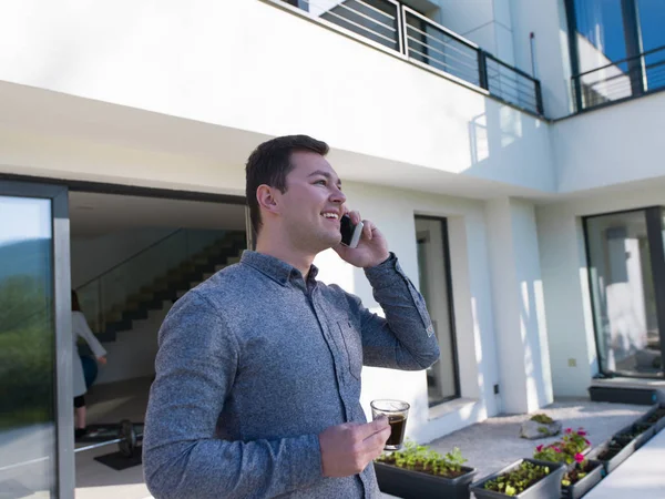 Hombre usando el teléfono móvil en frente de su villa de lujo —  Fotos de Stock